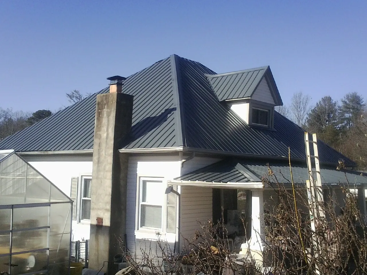 Dark blue standing seam metal roof on a white farmhouse with dormer — Slate & Tile Roof Repair by Roofing Brothers in French Lick