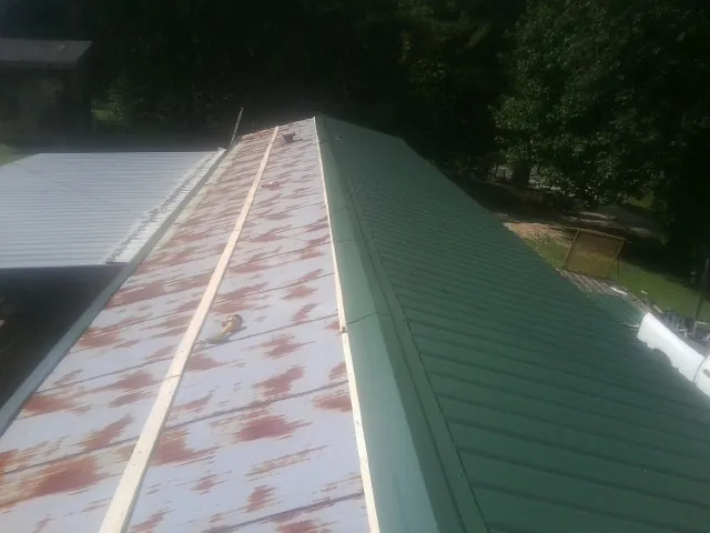 Old rusted panels beside newly installed green metal roofing — Wind Damage Roof Repair by Roofing Brothers in French Lick