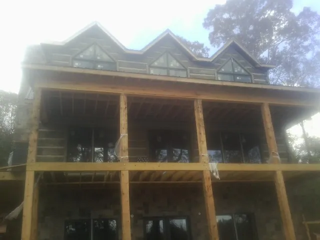 Dormers and porch framing on a large log home under construction — Roof Coating work by our crew in French Lick