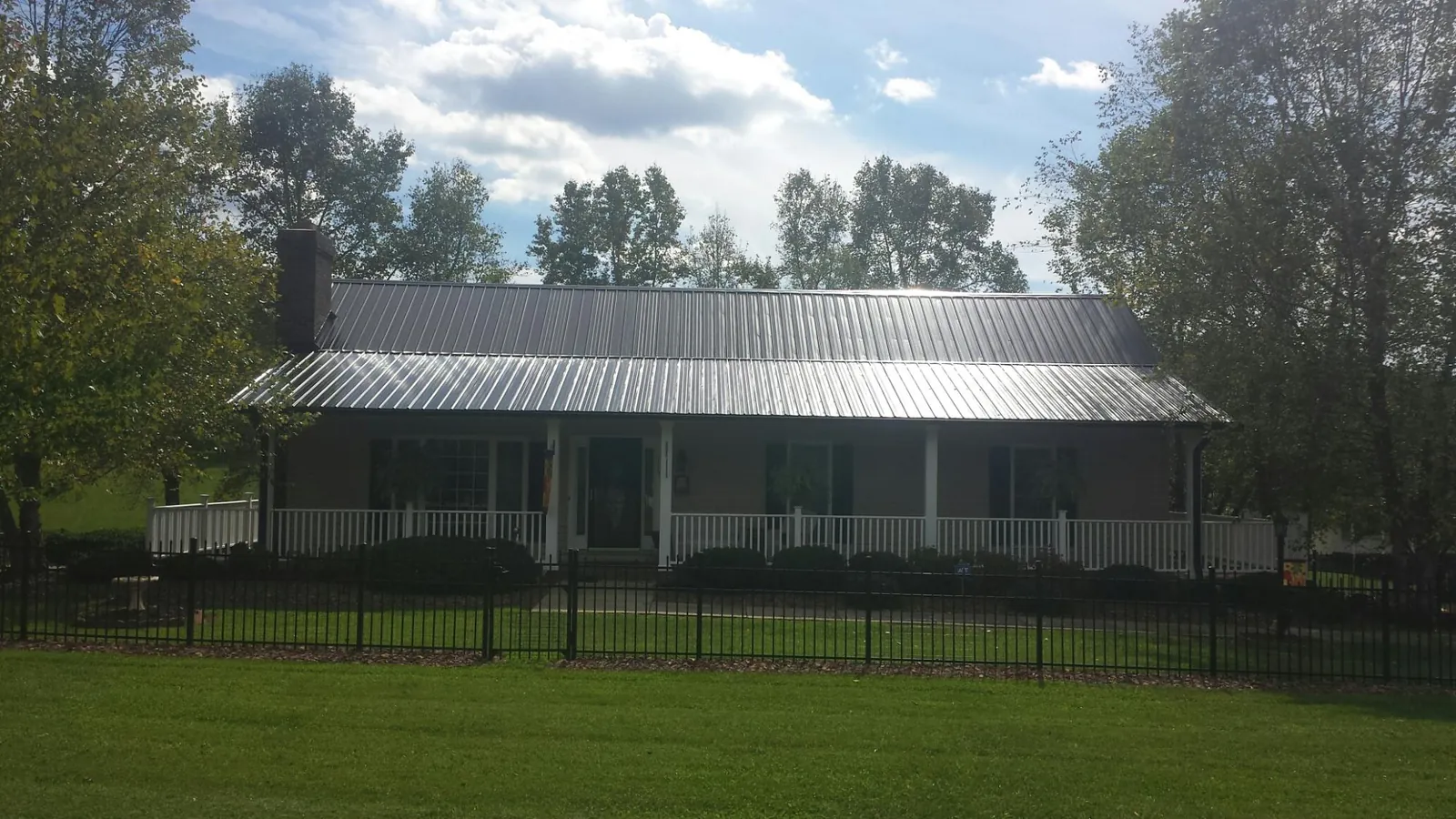 Gray metal roof on a brick ranch with a full width front porch — Gutter Guard Installation work by our crew in French Lick