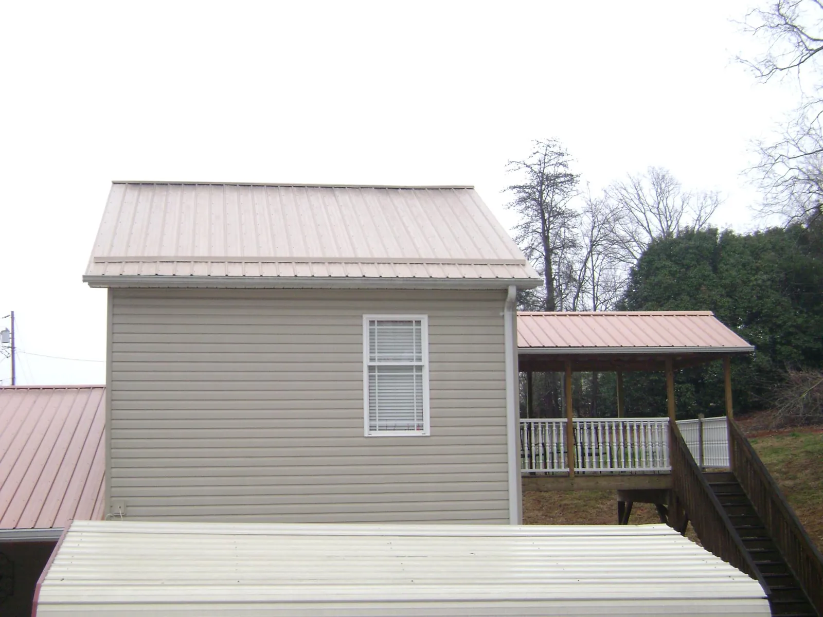 Tan metal roofs on a two story addition and attached porch, from a Roof Replacement job in French Lick