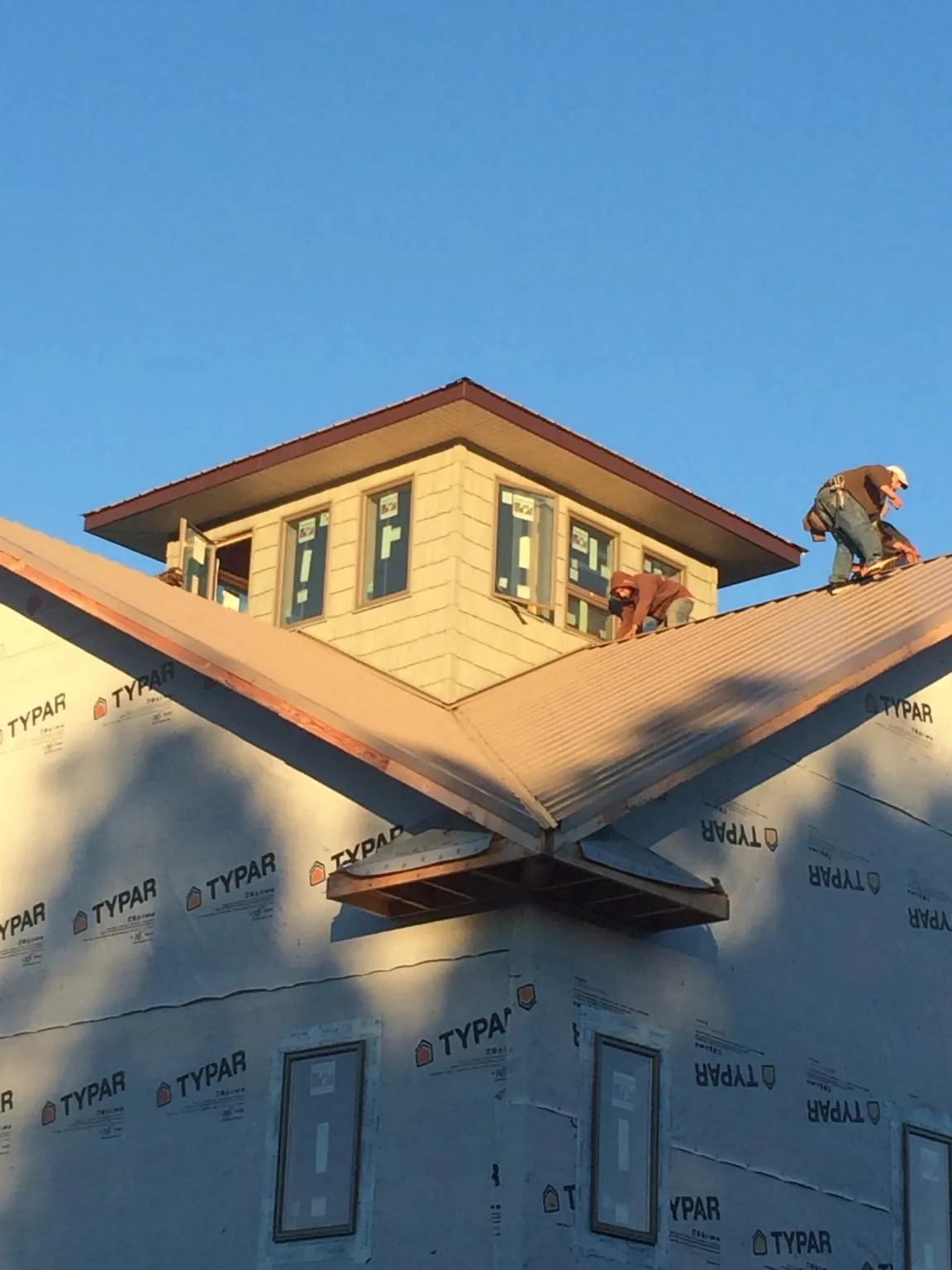 Roofers working around a rooftop cupola on a new metal roof at sunset — Roof Waterproofing in French Lick by Roofing Brothers